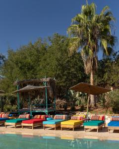 a group of lounge chairs and umbrellas next to a pool at Paradis Nomade in Azrarag
