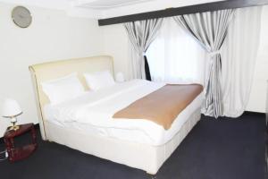 a white bed in a room with a window at KAA Highway Hotel in Mukono