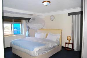 a bedroom with a large bed with a clock on the wall at KAA Highway Hotel in Mukono
