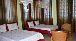 a bedroom with two beds and a table and a chair at KAA Highway Hotel in Mukono