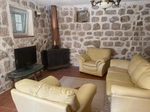 a living room with couches and a tv and a fireplace at Stoun house in Reževići