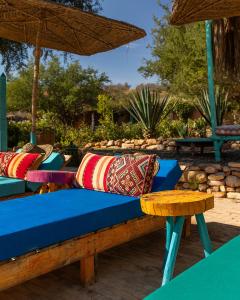 a bench with pillows and an umbrella on a patio at Paradis Nomade in Azrarag