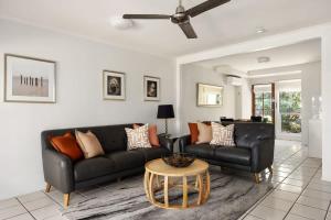 a living room with a black couch and a table at Riverside Rest on Noosa River in Noosaville