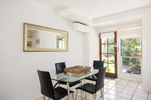a dining room with a glass table and black chairs at Riverside Rest on Noosa River in Noosaville