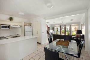 a kitchen and a living room with a glass table at Riverside Rest on Noosa River in Noosaville
