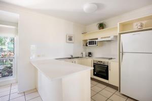 a white kitchen with a refrigerator and a stove at Riverside Rest on Noosa River in Noosaville +10 photos