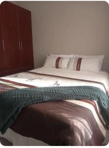 a bed with a green blanket on top of it at TnK Abode Apartments in Kathu