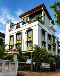 a white and yellow building with trees in front of it at Lofterra Luxury Apartment in Kozhikode city, calicut in Kozhikode