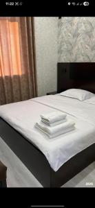 a bed with white towels stacked on top of it at Van park hotel in Shymkent