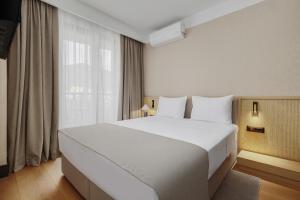 a bedroom with a large white bed and a window at Viale in Budva