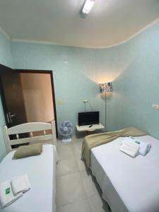 a room with two beds and a television in it at Pousada Allmar in Bertioga +33 photos