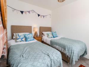 two beds in a bedroom with blue and green blankets at The Watch House in Weymouth