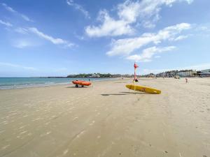 a beach with a yellow surfboard and a flag on it at The Watch House in Weymouth