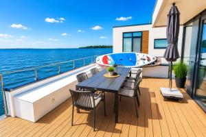 a deck on a yacht with a table and a boat at Floatinghouse Boddenperle in Ribnitz-Damgarten