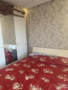 a bedroom with a red comforter on a bed at Perle de LAtlantique in Kenitra