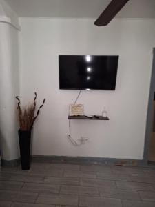 a flat screen tv on a white wall with a shelf at Casa en La zona Centro de la Ciudad in Ciudad Juárez