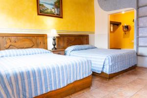 two beds in a room with yellow walls at Malarrimo Restaurant Hotel & RV Parking in Guerrero Negro