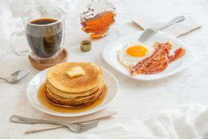 a table with plates of pancakes and a cup of coffee at Tropical Adventure Studios Suites HOTEL Beach CLUB & SPA in Punta Cana