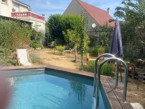 a swimming pool with an umbrella in a yard at Les Charmettes chambre double indépendante in Villemoisson-sur-Orge