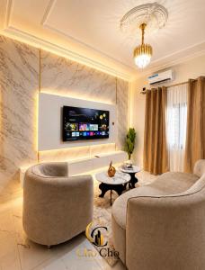 a living room with two chairs and a tv on a wall at ChoCho Apartments in Limbe
