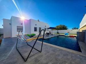 a hammock on the patio of a house with a swimming pool at Villa Safiya in Djerba