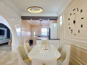 a dining room with a table and a clock on the wall at Villa Safiya in Djerba
