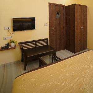 a room with a bed and a chair and a television at Hotel Royce By Glitz-Nxt to Visa Consulate & Kurla Station in Mumbai