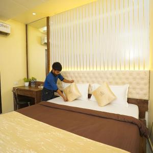 a man putting pillows on a bed in a room at Hotel Royce By Glitz-Nxt to Visa Consulate & Kurla Station in Mumbai +8 photos