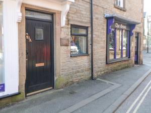 a brick building with a black door on a street at Cosy Cottage in Buxton