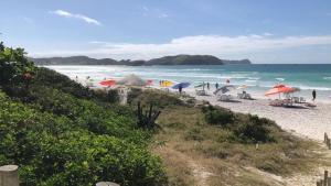 a beach with umbrellas and people on the beach at Apto MAR AZUL CARIBE - PRAIA DO FORTE - 3 minutos a pé da praia in Cabo Frio