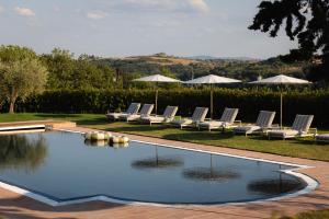 a pool with lounge chairs and umbrellas at The Podere Wine Resort Chianti in Barberino di Val dʼElsa
