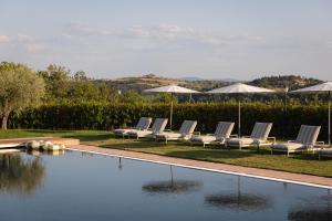 a row of lounge chairs next to a swimming pool at The Podere Wine Resort Chianti in Barberino di Val dʼElsa