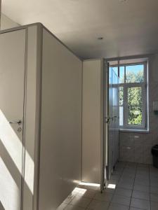 a white bathroom with a shower and a window at Spāres muiža in Spāres Muiža