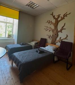 a room with two beds and a tree on the wall at Spāres muiža in Spāres Muiža