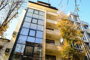 a tall building with glass windows and trees at Main Street Apartment in Sandanski