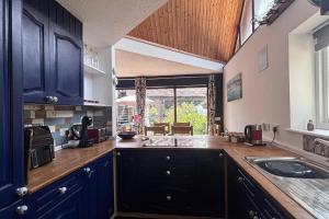 a large kitchen with blue cabinets and a sink at Sleeps 5 with in picturesque Chiddingly in Lewes