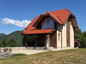 a house with an orange roof on a field at Apartmani JELIČIĆ in Zaovine