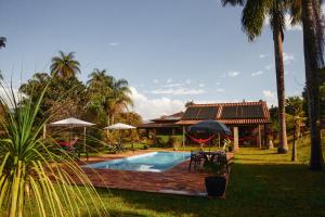 a swimming pool with umbrellas and a house at Pousada Capão da Coruja in Santa Bárbara