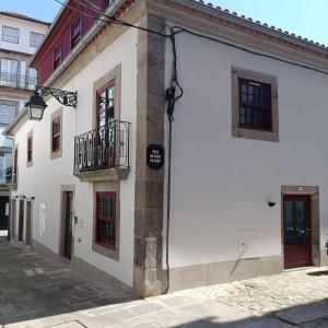 a white building with a balcony on a street at In Viana in Viana do Castelo