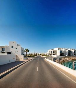 an empty road in front of some white buildings at Ajmal Villa in Al Ḩamrīyah