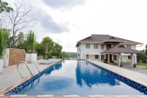 a swimming pool in front of a house at Winspark Inn Resort in Varkala