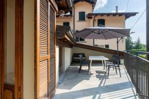 a balcony with a table and chairs and an umbrella at Mirafiume - Lugano Lake in Valsolda +27 photos