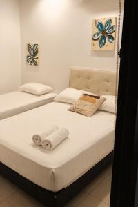 two beds in a room with towels on them at Hotel Riviera Central in Montería +8 photos