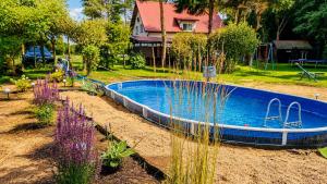 a swimming pool in a garden with purple flowers at Agroturystyka Anna in Dąbki
