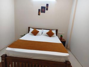 a bedroom with a bed with white sheets and orange pillows at Palazhi Stay 160m from Guruvayur Temple in Guruvāyūr