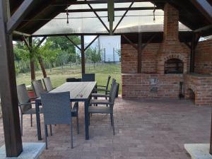 a patio with a table and chairs and a brick oven at Cinege Vendégház in Tolcsva