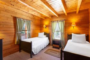 two beds in a room with wooden walls and windows at Rangeley Lake Resort in Rangeley +23 photos