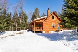 a log cabin in the snow with a porch at Rangeley Lake Resort in Rangeley