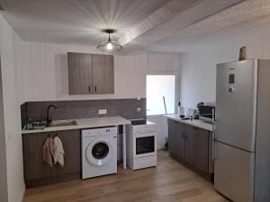 a kitchen with a washing machine and a refrigerator at Domaine de la Viloudard in Saint-Aignan