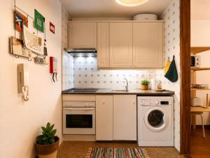 a kitchen with white cabinets and a washing machine at Studio Gerês in Geres